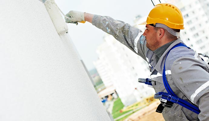 painter painting building exterior with roller