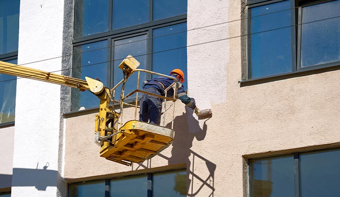 Professional worker painting exterior of a building
