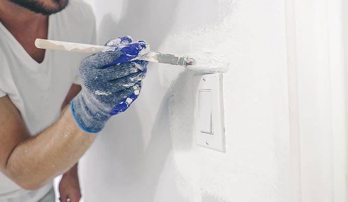 painter painting outside of electric switch
